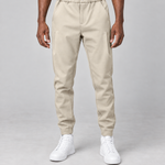 Vue de face recadrée d’un pantalon beige à taille élastiquée, poches latérales et chevilles resserrées.