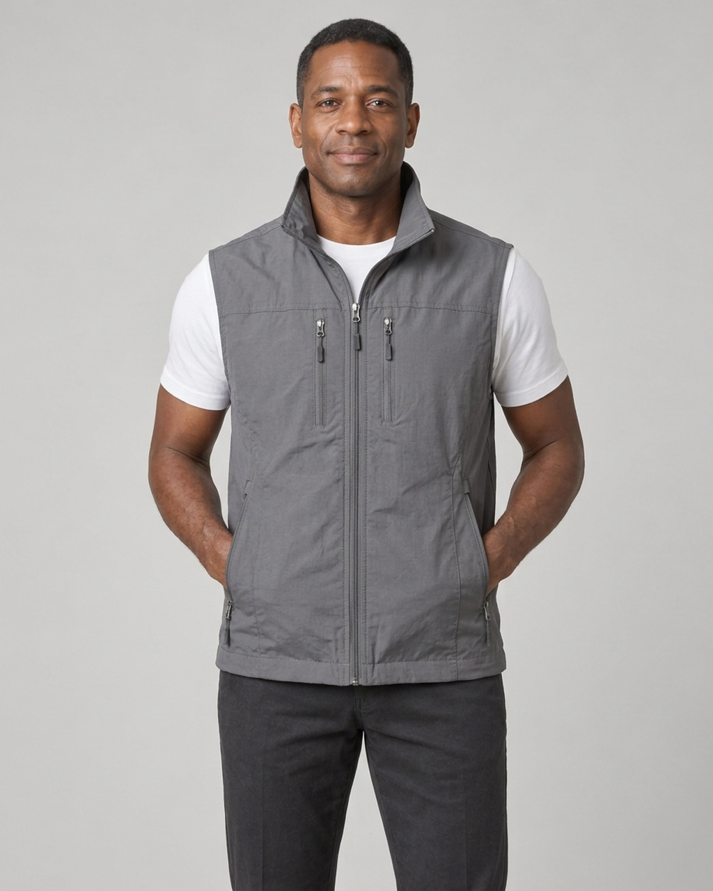 Homme portant un gilet gris zippé sans manches, avec col montant et quatre poches zippées, vue de face.