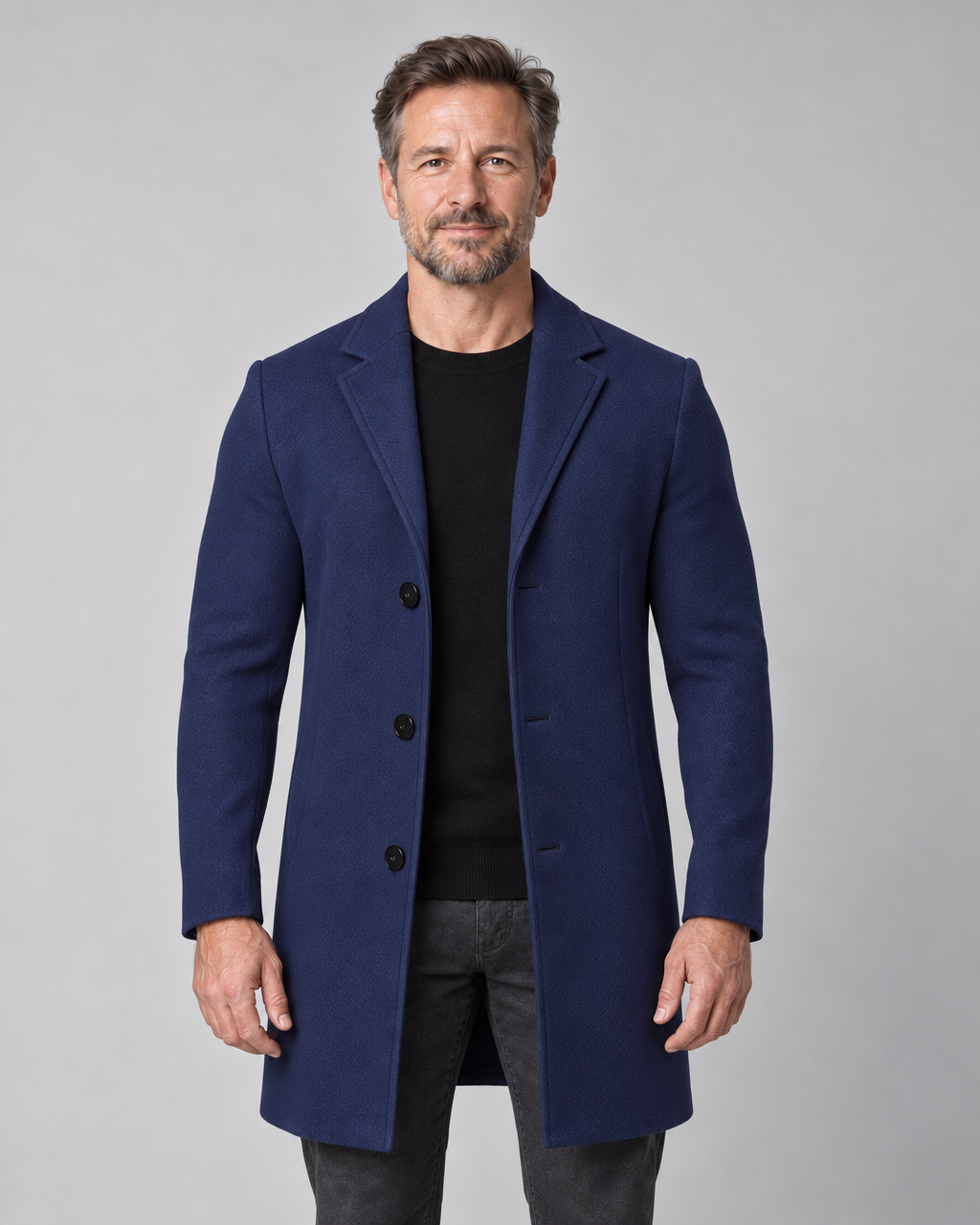 Manteau bleu marine à trois boutons, porté ouvert sur un pull noir, vue de face cadrée à mi-cuisses.