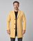 Vue de face recadrée d’un homme portant un manteau jaune moutarde à revers, trois boutons et poches latérales.