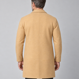 Homme portant un manteau beige clair, cadrage de dos jusqu’aux cuisses