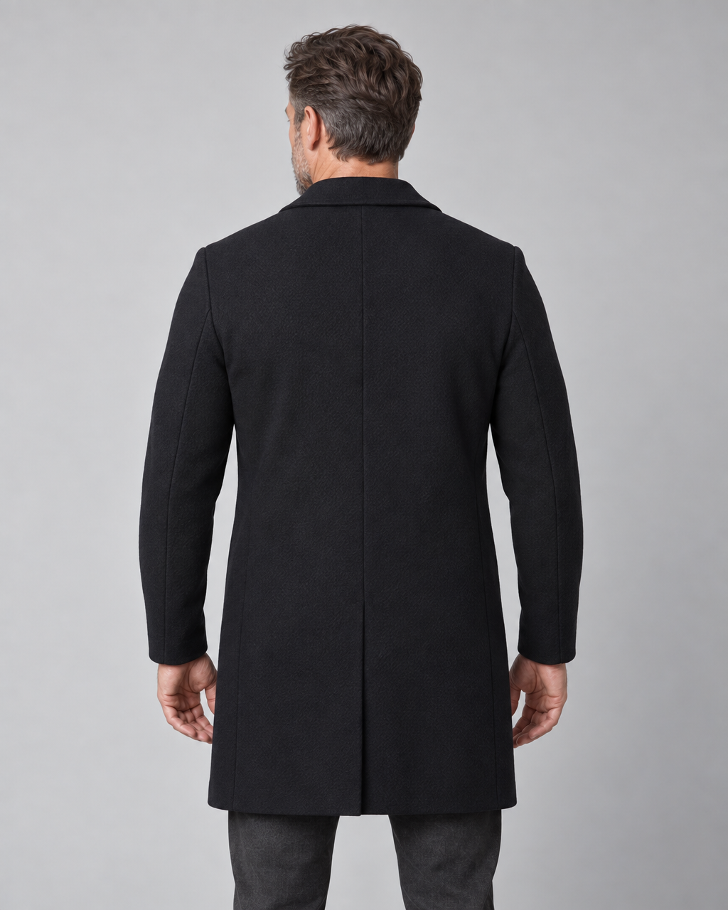 Homme vu de dos portant un manteau noir mi-long à col rabattu