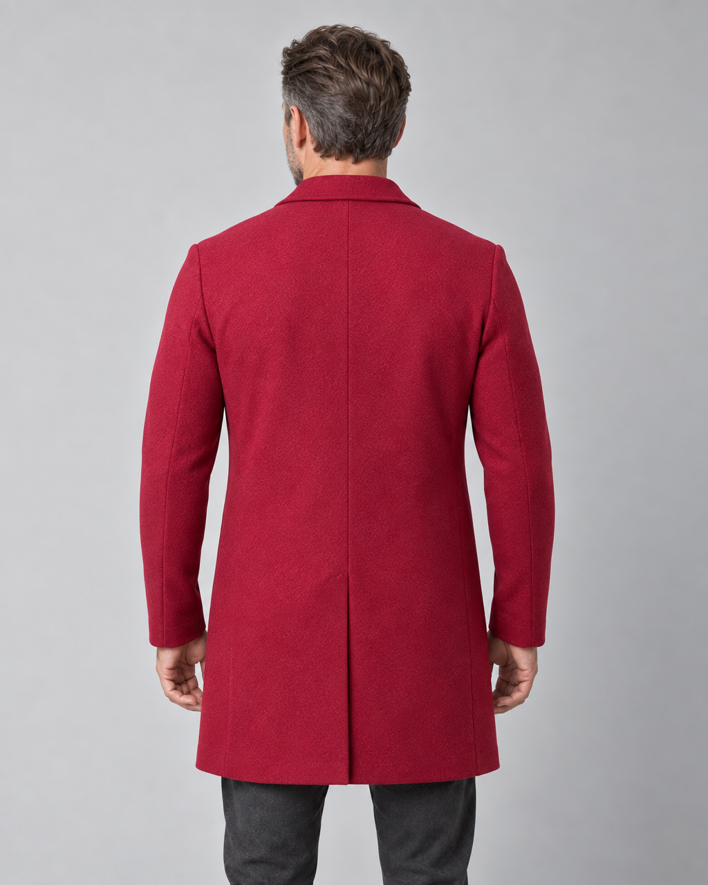 Homme portant un manteau rouge à manches longues, vue de dos cadrée de la tête aux cuisses.
