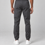 Vue arrière recadrée d’un pantalon gris foncé porté, avec taille et chevilles élastiquées.
