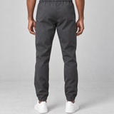 Vue arrière recadrée d’un pantalon gris foncé porté, avec taille et chevilles élastiquées.