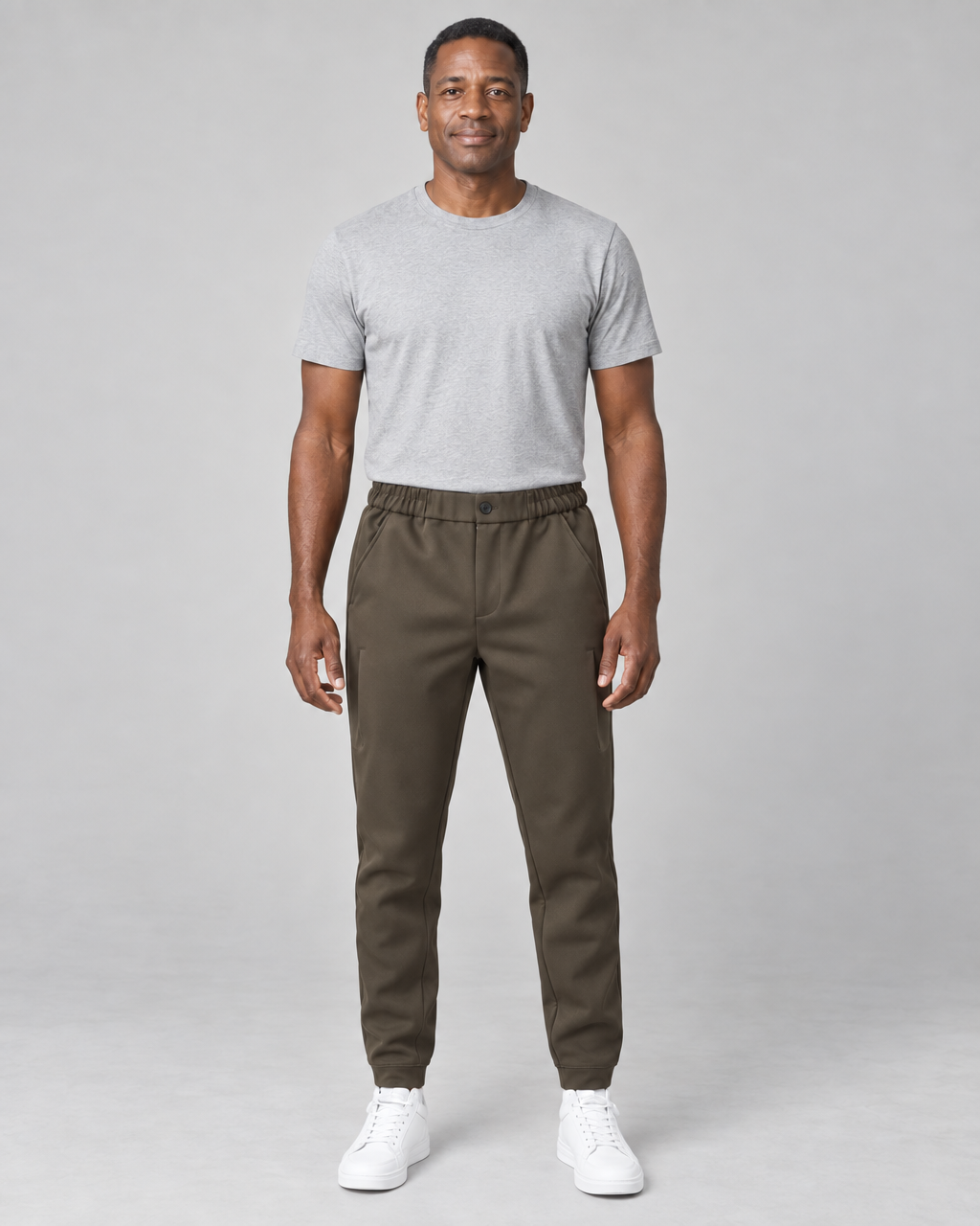 Homme portant un pantalon marron à taille élastiquée et chevilles resserrées, vue de face en pied