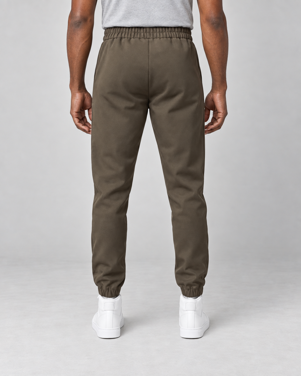 Vue arrière d’un pantalon marron à taille et chevilles élastiquées, porté avec des baskets blanches.
