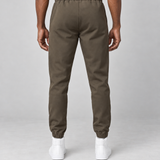 Vue arrière d’un pantalon marron à taille et chevilles élastiquées, porté avec des baskets blanches.