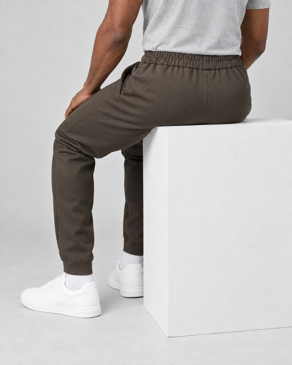 Pantalon de jogging marron porté en position assise, vu de dos, avec taille élastiquée et bas resserrés