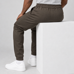 Pantalon de jogging marron porté en position assise, vu de dos, avec taille élastiquée et bas resserrés