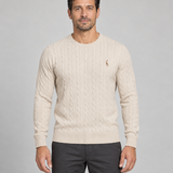 Pull beige clair à col rond et torsades, avec petit motif brun sur la poitrine, vue de face cadrée.