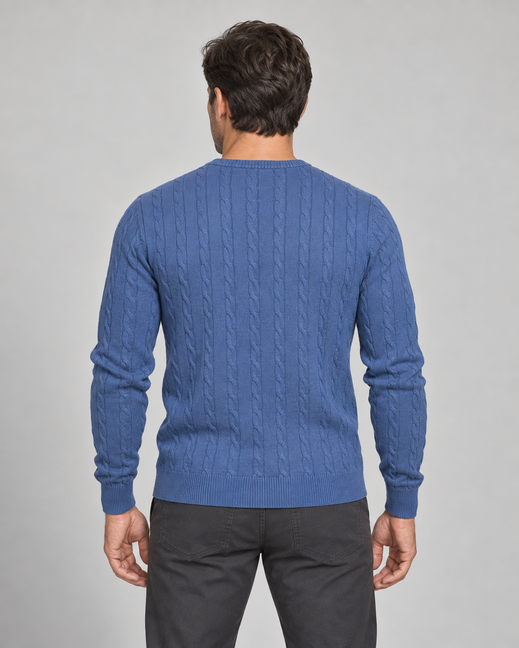 Homme vu de dos portant un pull bleu à torsades, avec manches longues et finitions côtelées.
