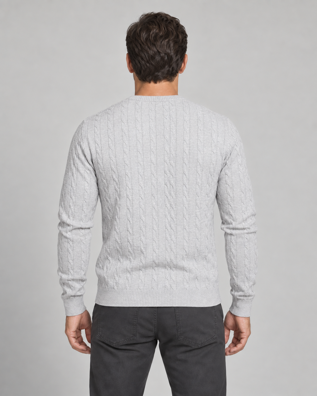 Vue de dos recadrée d’un homme portant un pull gris clair à torsades et manches longues.