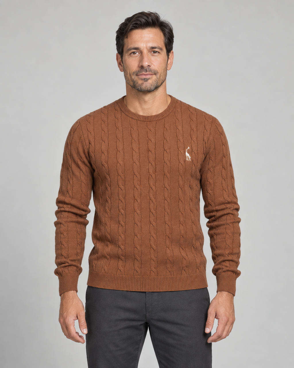 Homme portant un pull marron à col rond et torsades, avec un petit motif blanc sur la poitrine, vue de face.