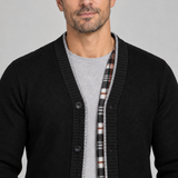 Vue rapprochée de face d’un cardigan noir à boutons, avec bordure grise et parement intérieur à carreaux.