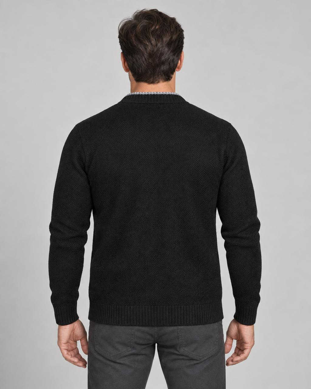 Homme de dos portant un cardigan noir à manches longues, cadré de la tête aux cuisses.