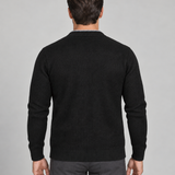 Homme de dos portant un cardigan noir à manches longues, cadré de la tête aux cuisses.