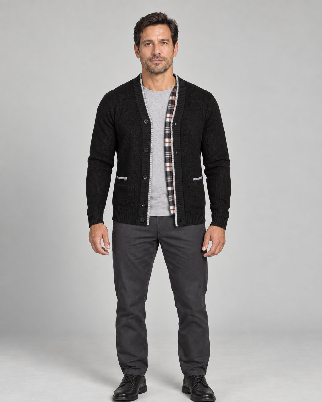 Homme en pied portant un cardigan noir boutonné, ouvert sur un T-shirt gris, vue de face.