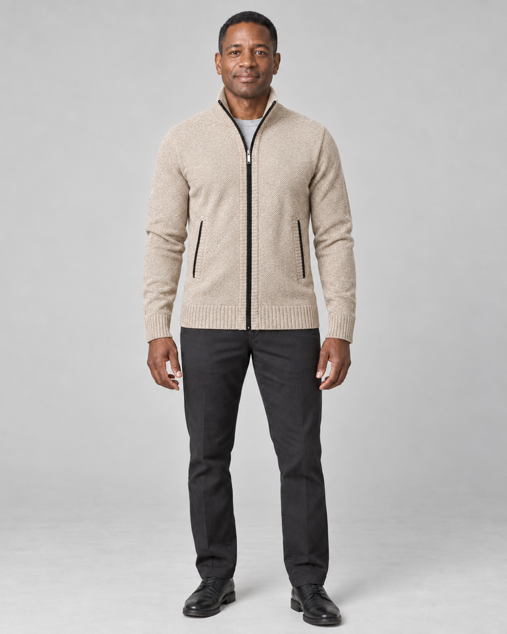 Homme de face en pied portant un gilet zippé beige à col montant et un pantalon noir.
