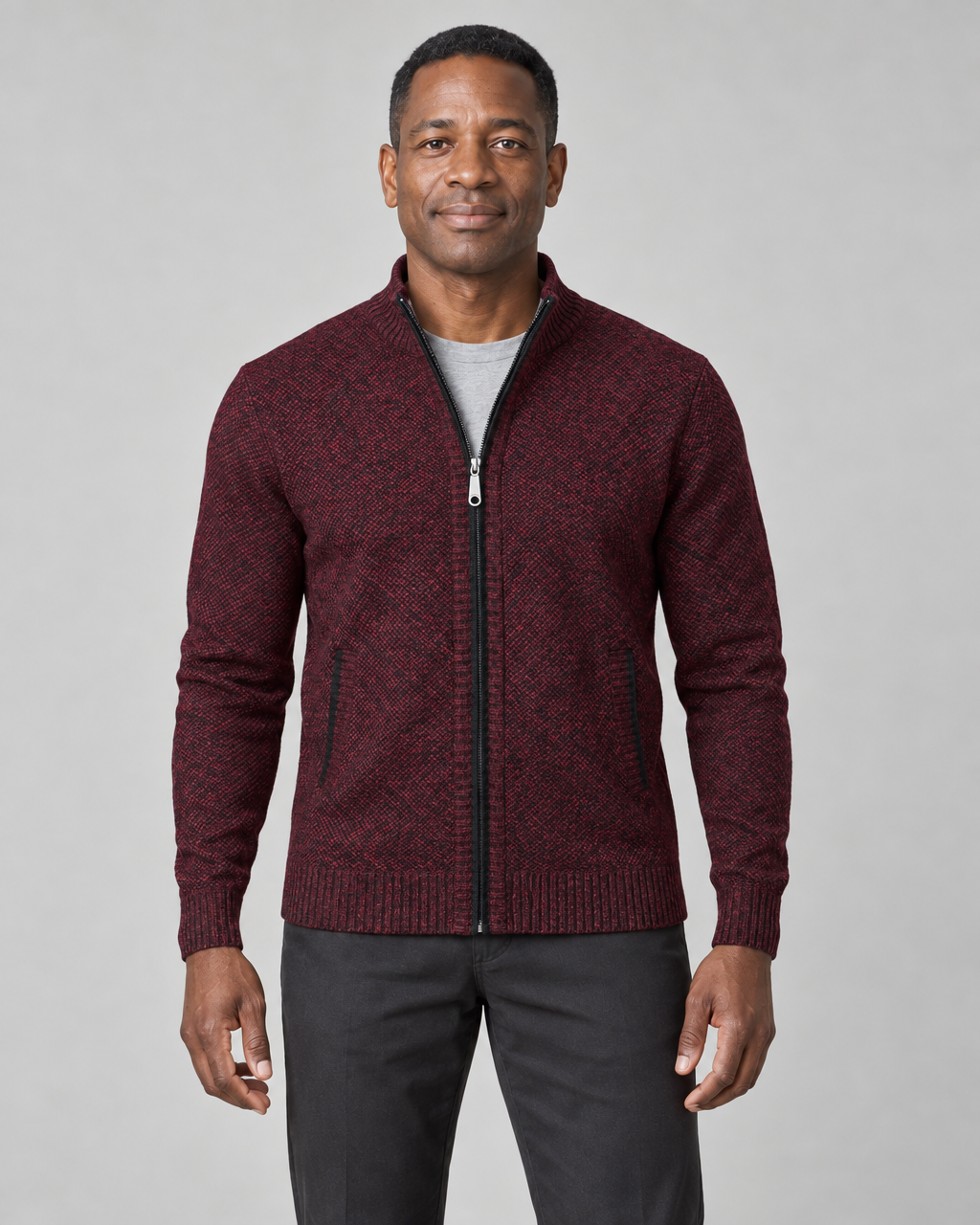 Homme portant un gilet zippé rouge vin à motif noir, vu de face et cadré à mi-cuisses.