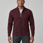 Homme portant un gilet zippé rouge vin à motif noir, vu de face et cadré à mi-cuisses.