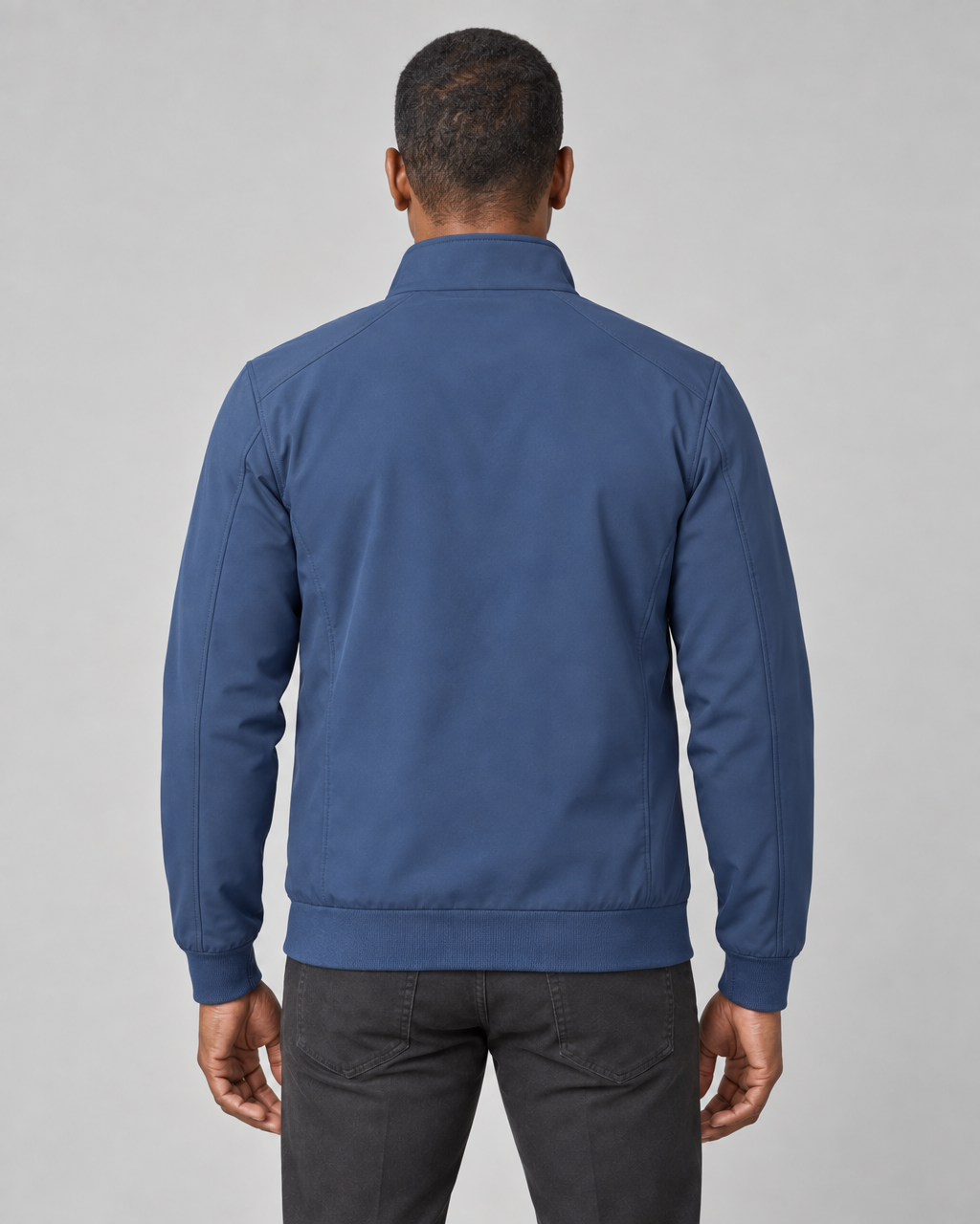 Dos d’une veste bleue portée, avec col montant, poignets et ourlet côtelés.