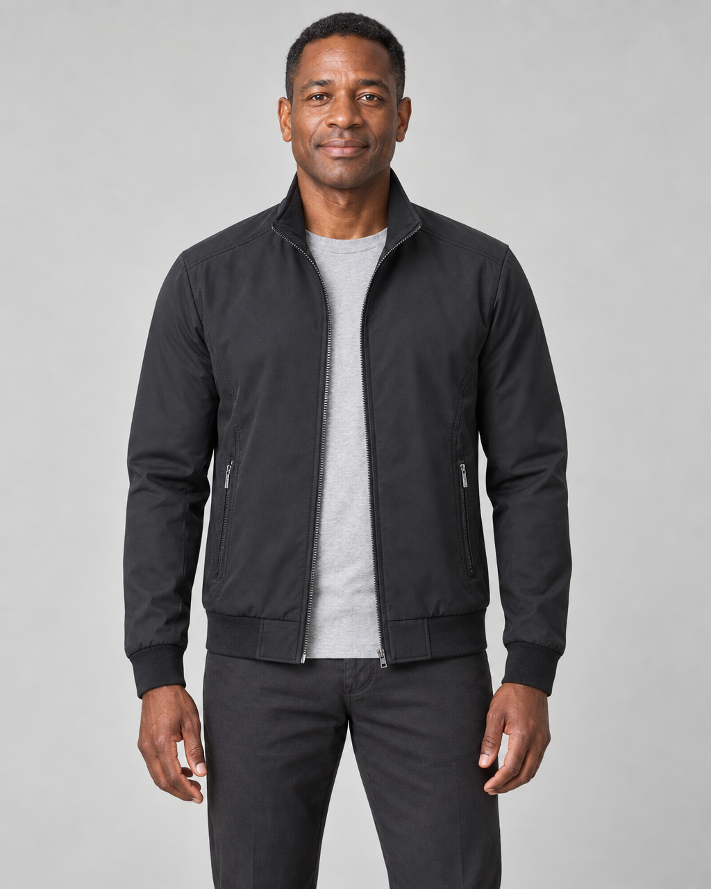 Homme portant une veste noire ouverte, vue de face, avec col montant et poches zippées.