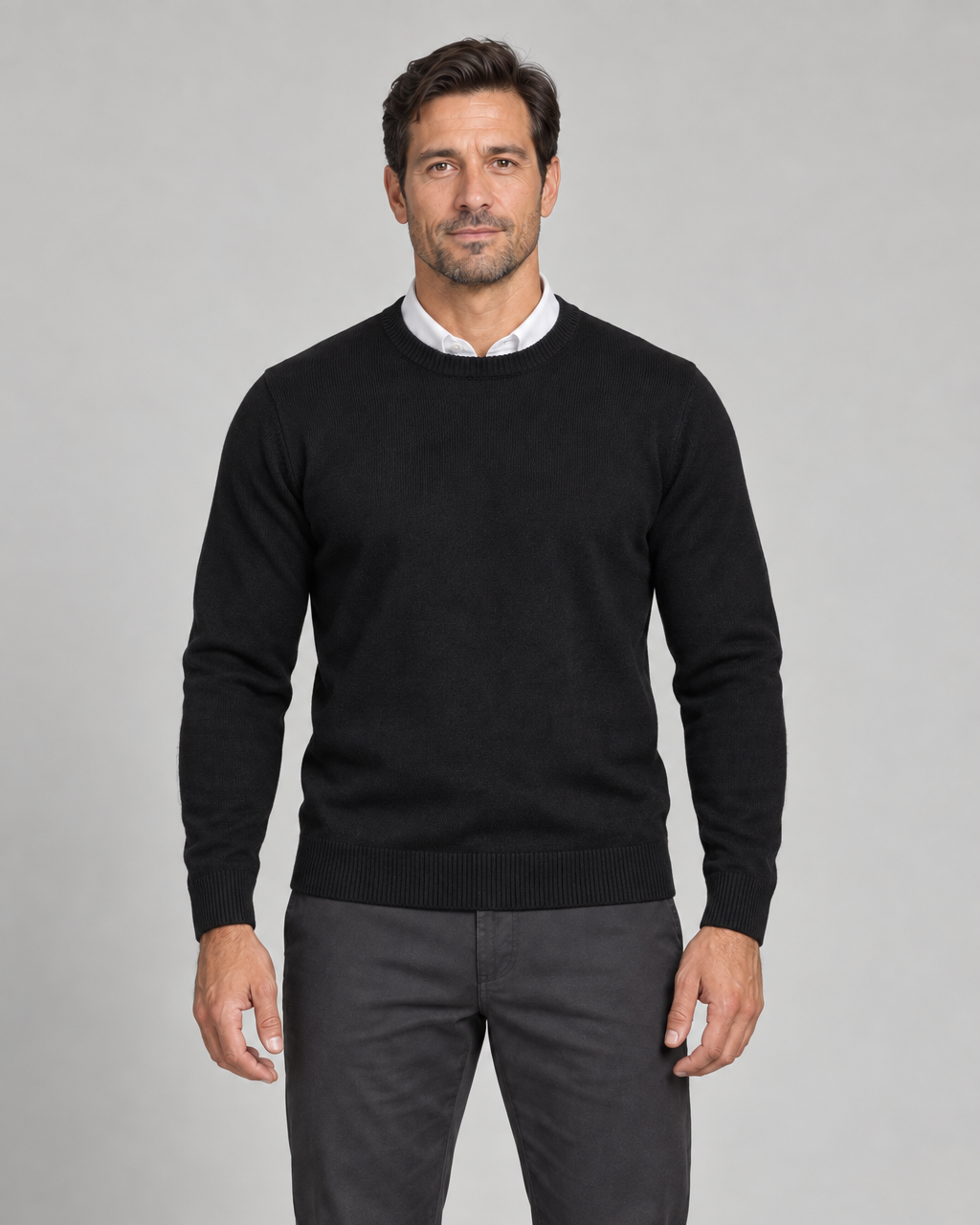 Homme portant un pull noir à col rond, manches longues, vu de face et cadré à mi-cuisses