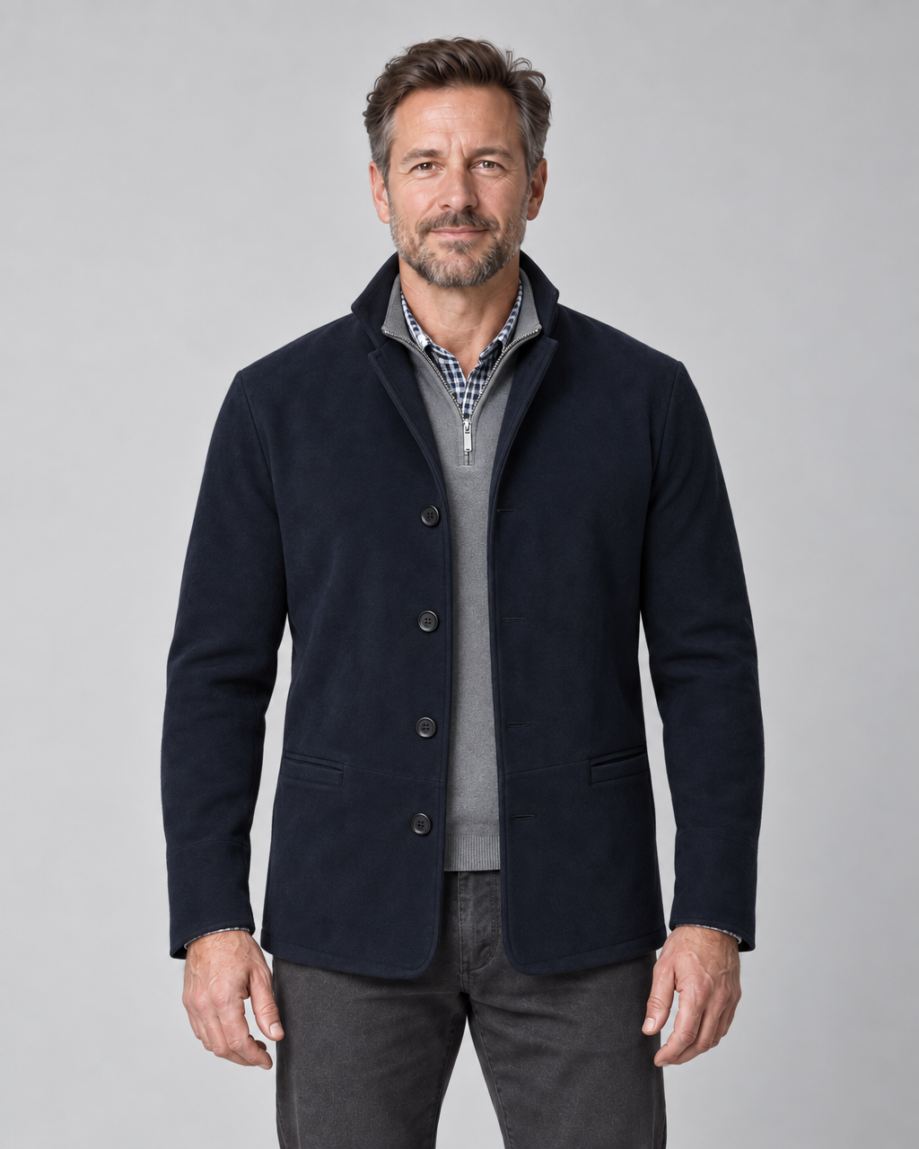 Blazer bleu marine pour homme, vue de face recadrée, porté sur un pull gris zippé et une chemise à carreaux.