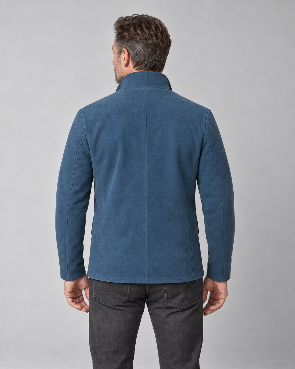 Homme portant une veste bleue à col montant, vue de dos, cadrée de la tête au haut des cuisses.