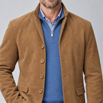 Vue rapprochée de face d’un blazer marron à quatre boutons et poches à rabat, porté sur un pull bleu.