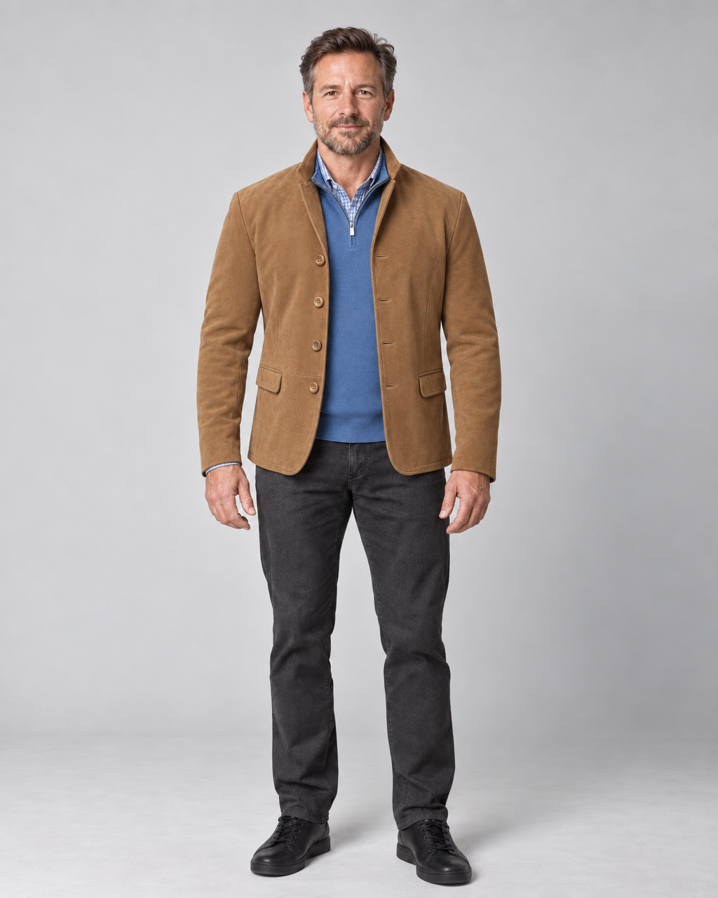 Homme en pied, vu de face, portant un blazer marron avec un pull bleu et un pantalon gris foncé.