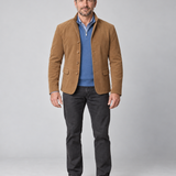 Homme en pied, vu de face, portant un blazer marron avec un pull bleu et un pantalon gris foncé.