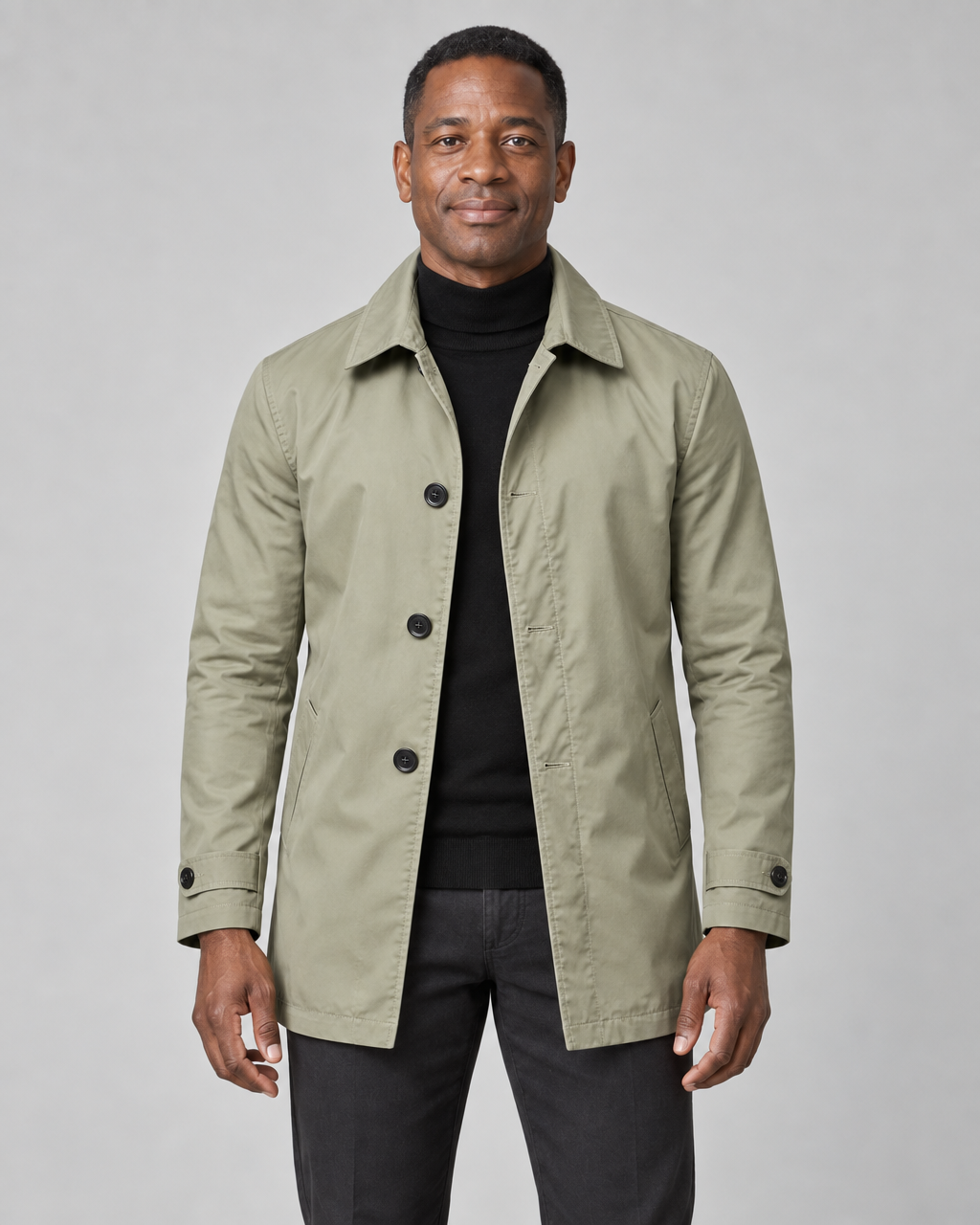 Manteau kaki mi-long à boutons noirs, col chemise et poches en biais, porté ouvert, vue de face cadrée.