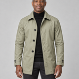 Manteau kaki mi-long à boutons noirs, col chemise et poches en biais, porté ouvert, vue de face cadrée.